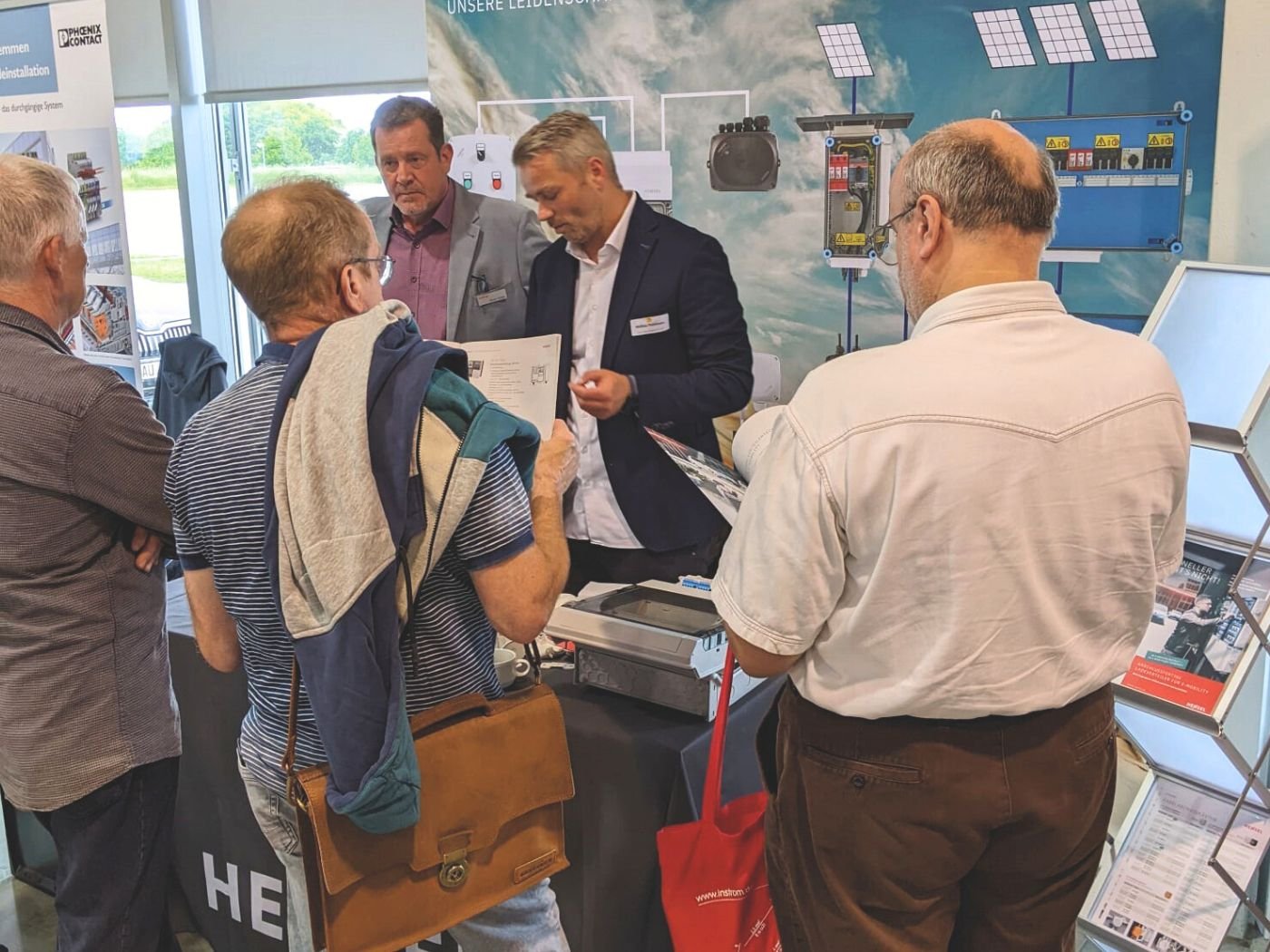 Bild zeigt einen Aussteller-Stand im Rahmen der Fachschulungstage 2024 in Nohra/Weimar. Ein mehrere Mitarbeiter ist mit Besuchern in ein Gespräch vertieft.