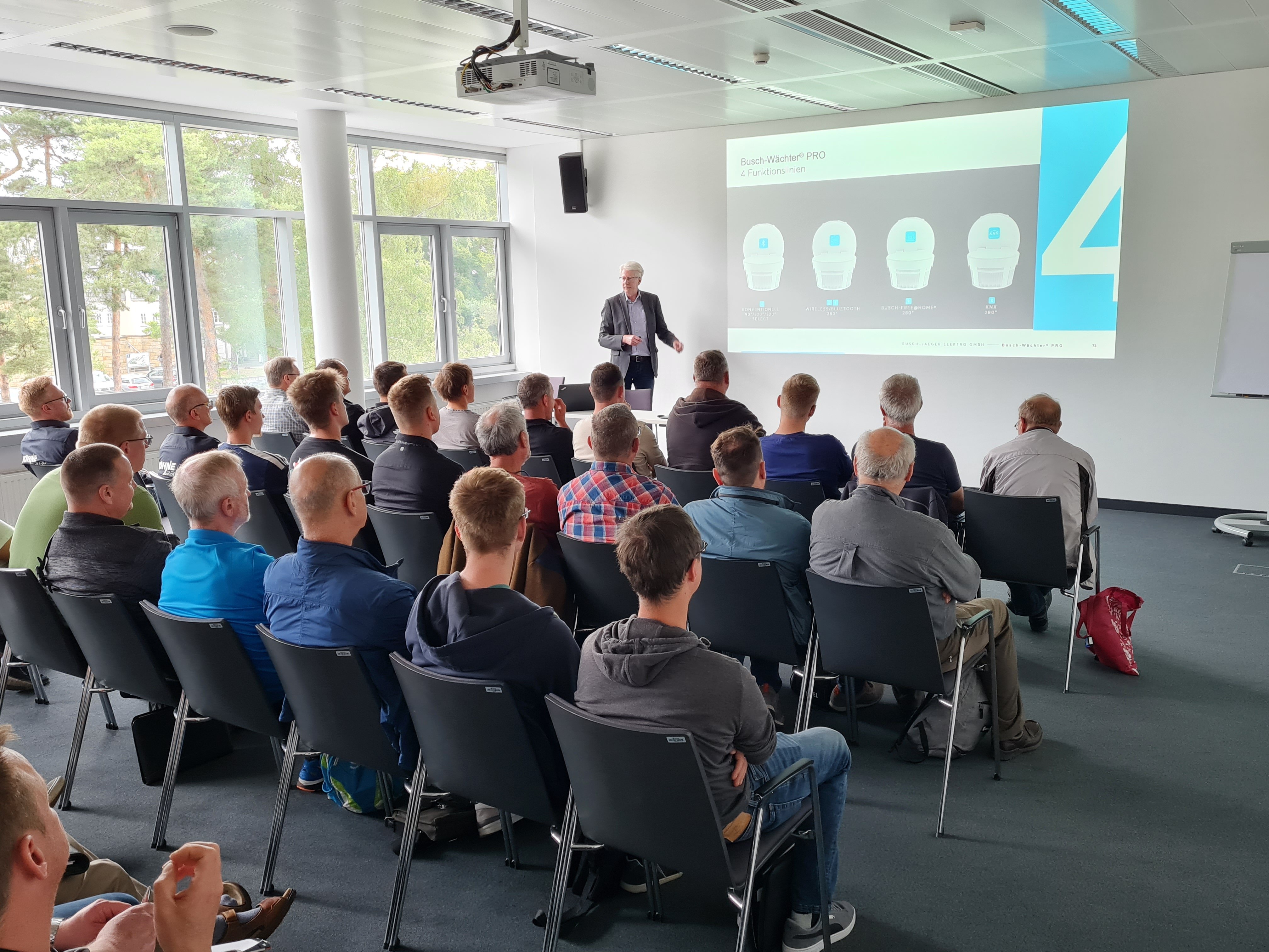 Bild mit Blick in den Veranstaltungsraum der Fachschulungstage 2024 in Dresden. Auf der Tribüne steht ein Referent der seinen Vortrag hält, in den Tischreihen davor sitzen die Teilnehmer.